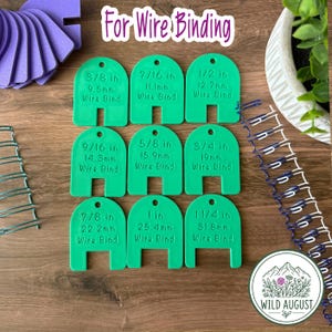 May include: Nine green plastic wire binding size gauges arranged in a grid. Each gauge features a hole at the top and text indicating measurements from 3/8 in to 1 1/4 in. The text "For Wire Binding" appears at the top, with wire coils visible.