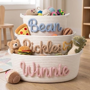 May include: A white ceramic mug with a black handle and the text "But First, Coffee" in a bold, black font. The mug is set against a blurred background, suggesting a cozy setting.