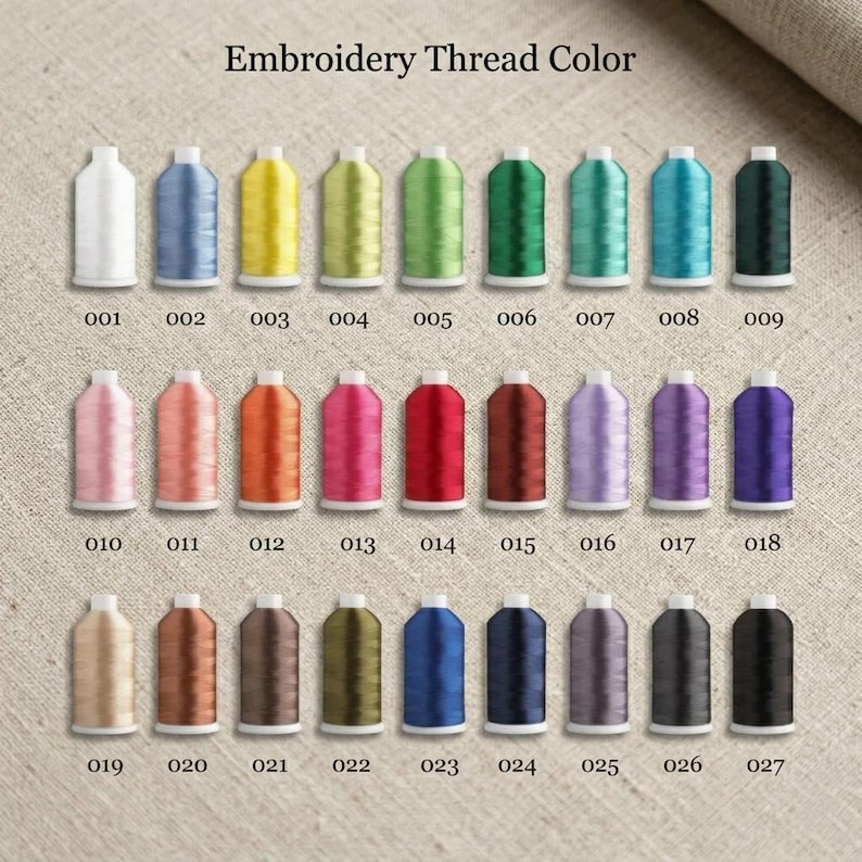 May include: A collection of twenty-seven spools of embroidery thread arranged in three rows of nine. Each spool is labeled with a numerical code from 001 to 027, displaying a wide spectrum of colors including white, yellow, green, blue, pink, red, and black.