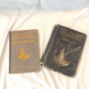 May include: Two vintage books titled "The Elson Readers." One is a Pupil's Hand Chart, the other is Book One. Both books have gold lettering and illustrations on the covers. The books are on a white background.