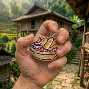 May include: Embroidered patch featuring a basket of breadsticks and a small bowl of dipping sauce. The patch has a woven basket design with a red and white checkered cloth. The breadsticks have smiling faces.