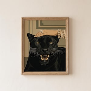 May include: Framed art print featuring a black panther with an open mouth, revealing its teeth. A hand adorned with jewelry rests on the panther's head. The artwork is set against a neutral background and framed in a light wood.