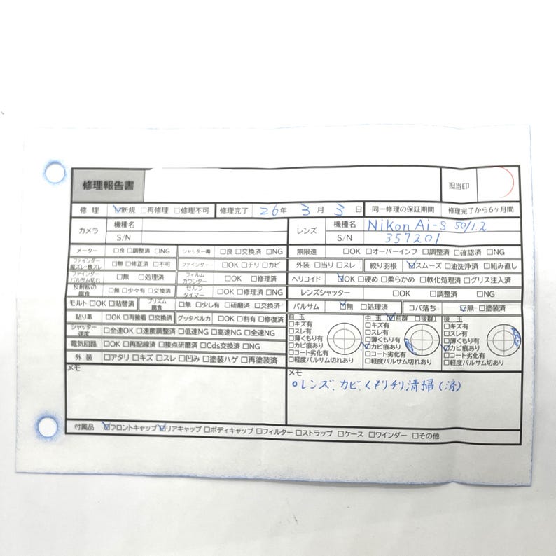 Może przedstawiać: Biały dokument z japońskim tekstem, zawierający słowa "Nikon Ai-S 50/12" i numer seryjny "357201". Dokument wygląda na raport naprawy, z r&oacute;żnymi polami wyboru i odręcznymi notatkami.