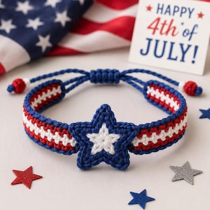 May include: A crocheted bracelet featuring a central blue star with a white center, attached to a band of red, white, and blue stripes. The bracelet has adjustable blue cords with small red beads at the ends, showcasing a patriotic color scheme.