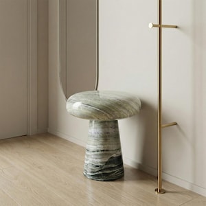 May include: A marble side table in the shape of a mushroom, with a circular top and a flared base. The table has a green and grey colour scheme, with a natural stone pattern. It is a decorative accent piece.