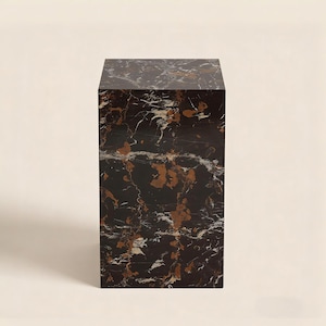 Peut inclure: Un piédestal rectangulaire en marbre noir avec des veines cuivrées et blanches. Le bloc de pierre est de conception solide et moderne, adapté à l'exposition d'art ou de décoration. La surface est polie.