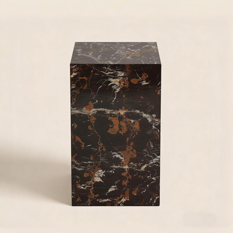以下が含まれることがあります： 銅と白の縞模様が入った長方形の黒大理石の台座。石のブロックは、アートや装飾の展示に適した、頑丈でモダンなデザインです。表面は研磨されています。