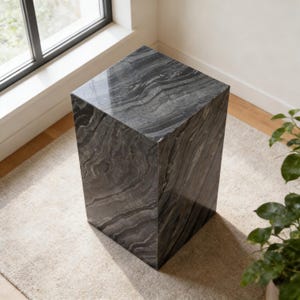 以下が含まれることがあります： 暗い灰色の立方体型のマーブル台座。石には、より明るい色と暗い灰色の自然な渦巻き模様があります。台座は窓と鉢植えの植物の近くの明るいベージュのラグの上に置かれています。立方体の高さは約46cmです。