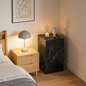 以下が含まれることがあります： 木製のナイトスタンドとランプを備えた寝室のインテリア。黒い大理石のサイドテーブルには、キャンドル、ディフューザー、バストが飾られています。額入りの抽象芸術作品が壁に掛けられています。