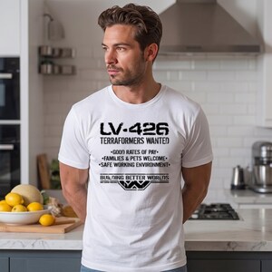 May include: A white short-sleeved t-shirt featuring black distressed text that reads LV-426 TERRAFORMERS WANTED, GOOD RATES OF PAY, FAMILIES & PETS WELCOME, SAFE WORKING ENVIRONMENT, and BUILDING BETTER WORLDS with a Weyland-Yutani logo graphic.