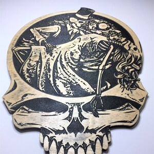 May include: A wooden skull with a black and white image of a skeleton couple dancing inside the skull. The skeleton couple is wearing a top hat and a dress.