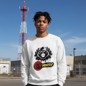 Könnte beinhalten: Weißes Sweatshirt mit einem Grafikmotiv eines Affen mit Sonnenbrille und Kapuzenpullover, vor einer Skyline. Der Text "City Monkey" ist darunter im Graffiti-Stil geschrieben. Ein lässiges Streetwear-Kleidungsstück.