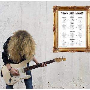 Könnte beinhalten: Eine Person mit langen, lockigen blonden Haaren spielt eine weiße E-Gitarre mit Ahornhals. Ein gerahmtes Poster an der Wand zeigt Gitarrenakkorddiagramme und den Text "Shred with Triads!". Ein PDF-Download-Symbol ist sichtbar.