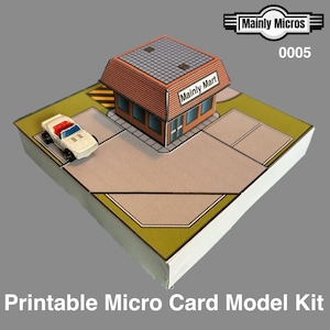 May include: A miniature card model kit of a convenience store, labeled "Mainly Mart," with a small white car. The model has a brown roof and tan parking area. The text "Printable Micro Card Model Kit" is at the bottom.