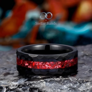 May include: A black ring with a hammered texture and a vibrant red inlay. The ring is set against a blurred background with the text "Stellar Bands". The ring is a bold statement piece.