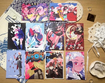 Puede incluir: Una colección de once láminas artísticas rectangulares con diversas ilustraciones de personajes estilo anime en colores vibrantes, incluyendo rosa, azul, rojo y negro. Las láminas están dispuestas sobre una superficie junto a una bolsa de tela blanca con patrones de olas azules, dos posavasos de ganchillo blancos, una pequeña pirámide negra y un cuenco de cerámica blanca que contiene un cristal transparente.