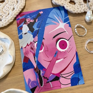 Puede incluir: Una colorida impresi&oacute;n art&iacute;stica que presenta una ilustraci&oacute;n estilizada de un personaje con piel rosa y cabello azul. La obra de arte presenta un gesto de dedo en los labios y una paleta de colores vibrantes.