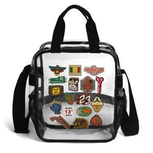 May include: A clear plastic tote bag with black trim, black handles, and a black shoulder strap. The front of the bag features a collection of colorful, varied graphic patches including text like American Cars, Downfall, and Porch Light.
