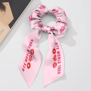 Può includere: Fascetta per capelli rosa con motivo floreale e lunghi nastri. I nastri presentano il testo "BTS WORLD TOUR" in rosso. L'accessorio per capelli è realizzato in tessuto setoso ed è progettato per lo styling dei capelli.