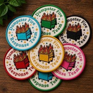 May include: A collection of seven circular embroidered patches featuring a dumpster on fire with the text Dumpster Fire Response Team. The patches come in various colors including light blue, green, black, red, yellow, pink, and teal.