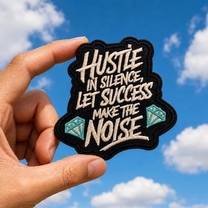 May include: A black embroidered patch with a scalloped edge featuring the white text Hustle in silence, let success make the noise and two light blue diamond icons on the sides. The patch has a thick black border and a textured fabric finish.
