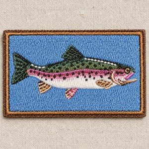 May include: A rectangular embroidered patch featuring a rainbow trout with a dark green back, black spots, and a vibrant pink lateral stripe. The fish is centered on a light blue background, all enclosed within a thick, dark brown stitched border.