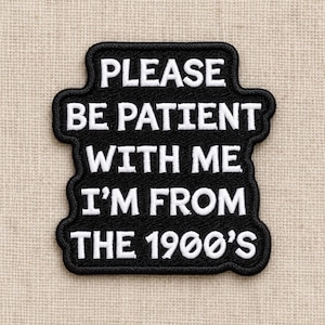 May include: A black embroidered patch with white text that reads PLEASE BE PATIENT WITH ME I'M FROM THE 1900'S. The patch has a rounded rectangular shape with a thick black border and a textured fabric finish throughout the entire design.