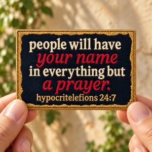 May include: A rectangular embroidered patch with a black background and a gold border. The text reads: people will have your name in everything but a prayer. hypocritelefions 24:7. The words your name and a prayer are stitched in red thread.