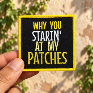 May include: A square embroidered patch with a black background and a bright yellow border. The text reads WHY YOU STARIN' AT MY PATCHES in a mix of yellow and white embroidered lettering, featuring a bold, block-style font throughout the design.