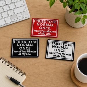 May include: Three rectangular embroidered patches with white text on red, black, and white backgrounds. Each patch reads: I TRIED TO BE NORMAL ONCE, Worst Two Minutes of My Life. The patches feature a simple border and are arranged on a flat surface.