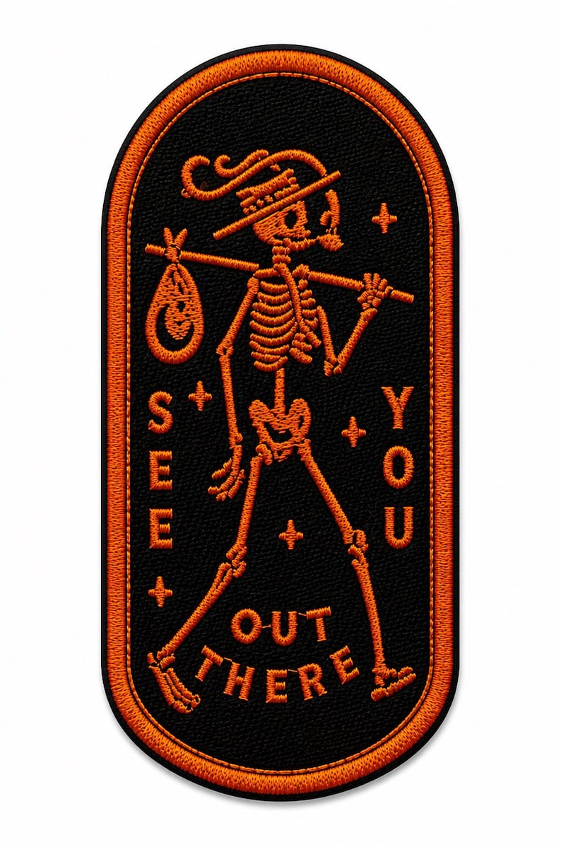 May include: An oval-shaped embroidered patch with a black background and orange border. It features an orange skeleton wearing a hat, carrying a bindle on a stick, and the text "SEE YOU OUT THERE" with small plus signs and stars.