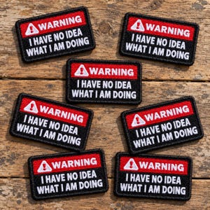 May include: Six rectangular embroidered patches featuring a red top border with a white warning triangle icon and the word WARNING in white text. The black lower section displays the white text I HAVE NO IDEA WHAT I AM DOING.