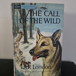 May include: Vintage book cover for "The Call of the Wild" by Jack London. The cover features a detailed illustration of a dog with its tongue out, set against a snowy forest scene with a dog sled. The book is part of the Companion Library.