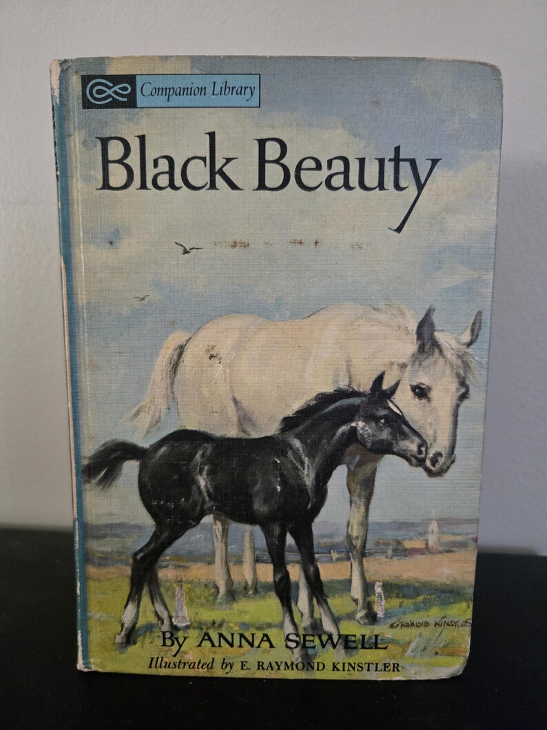 May include: Vintage hardcover book titled "Black Beauty" by Anna Sewell. The cover features a painting of a black foal and a white horse in a field. The book is part of the Companion Library series.