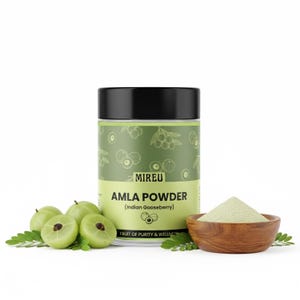 Puede incluir: Un recipiente cilíndrico de "MIREU Amla Powder (Indian Gooseberry)" con tapa negra, etiqueta verde e ilustraciones. Un pequeño cuenco de madera contiene un montón de polvo verde. Cerca se disponen grosellas verdes frescas y hojas.