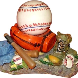 Puede incluir: Figura decorativa con temática de béisbol que presenta una pelota de béisbol sobre un guante naranja, con un bate de béisbol, una gorra azul y un par de botas. También hay varias pelotas de béisbol presentes. La figura está sobre una base texturizada.