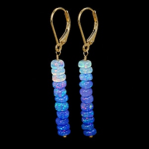 May include: A pair of drop earrings featuring gold-tone leverback closures and vertical strands of round, iridescent opal beads. The beads transition in color from a pale, translucent white at the top to a deep, vibrant blue at the bottom.