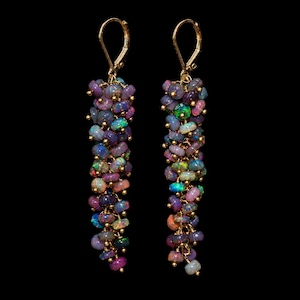 May include: A pair of long dangle earrings featuring clusters of small, round, iridescent opals in shades of purple, blue, and green. Each earring is suspended from a gold-toned leverback clasp, with the opals arranged in a dense, cascading formation.