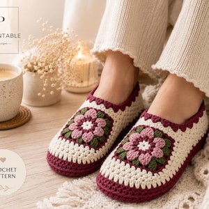 Peut inclure: Une paire de chaussons crochetés à la main avec une base couleur crème et un motif floral central dans des tons rose poudré et vert olive. Les chaussons présentent une bordure bordeaux foncé le long de la semelle et du col, en granny square.