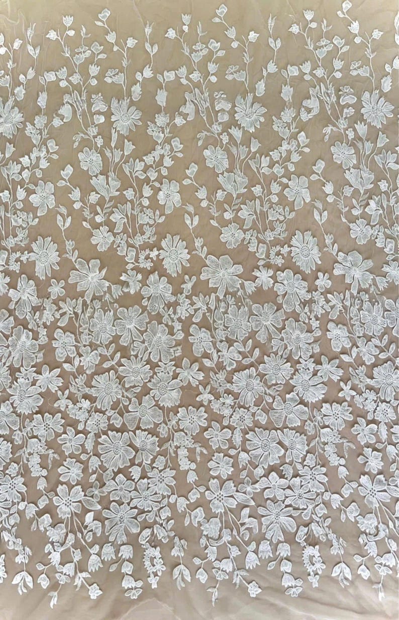 K&ouml;nnte beinhalten: Wei&szlig;er floraler Spitzenstoff mit einem detaillierten Muster aus verschiedenen Blumenarten und Bl&auml;ttern. Die Spitze ist dicht bestickt und erzeugt eine strukturierte Oberfl&auml;che. Der Hintergrund ist hellbeige und bildet einen Kontrast zur wei&szlig;en Spitze.