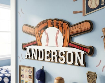 Op de afbeelding: Houten wanddecoratie met honkbalthema met een honkbal, handschoen en gekruiste knuppels. De naam "ANDERSON" wordt in witte letters weergegeven. De decoratie omvat een wimpel, een honkbal en een Little League-trofee.
