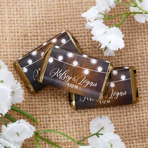 May include: Three small chocolate bars wrapped in brown paper with white string lights and the text "Kelsey & Logan 9.12.18" printed on them.