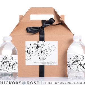 May include: A brown cardboard box with a black ribbon and two clear water bottles with black and white labels. The labels have the text "Charlise and Ryan" and the date "09.22.26". The box also has a label with the text "Thank you for celebrating with us September 22, 2026".