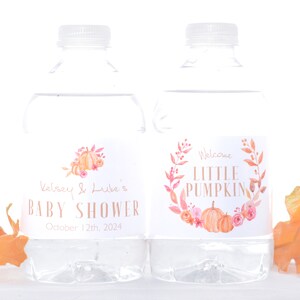 May include: Two clear plastic water bottles with labels. The label on the left bottle says "Kelsey & Luke's Baby Shower October 12th, 2024". The label on the right bottle says "Welcome Little Pumpkin" with a watercolor illustration of pumpkins and flowers.