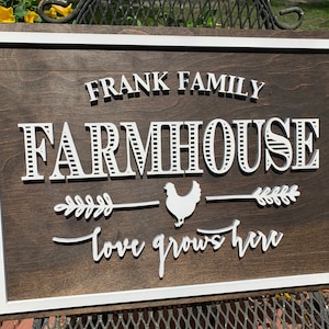 May include: A white wooden farmhouse sign with the text "FRANK FAMILY FARMHOUSE" in a decorative font. A white chicken silhouette is centered between two white wheat stalks with the text "love grows here" below.