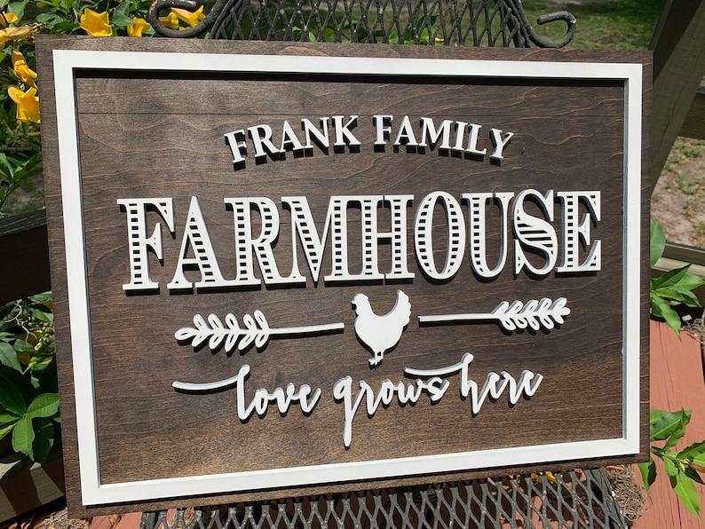 May include: A white wooden farmhouse sign with the text "FRANK FAMILY FARMHOUSE" in a decorative font. A white chicken silhouette is centered between two white wheat stalks with the text "love grows here" below.