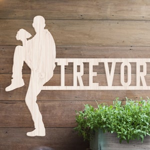 May include: Wooden silhouette of a person in a baseball pose with the name "TREVOR" cut out below.