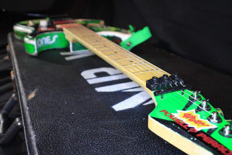 May include: A white ceramic mug with a black handle and the text "But First, Coffee" in a bold, black font. The mug is set against a blurred background, suggesting a cosy setting.