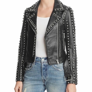 May include: Black leather jacket with silver stud embellishments. The jacket features a classic biker style with a notched collar, asymmetrical zip closure, and a belt at the waist. The sleeves and shoulders are heavily studded.