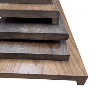 May include: A selection of wooden planks in different sizes and profiles. The planks are a rich brown hue, showcasing the natural wood grain. Some have rounded edges, others are square. The planks are stacked, demonstrating their varying dimensions.